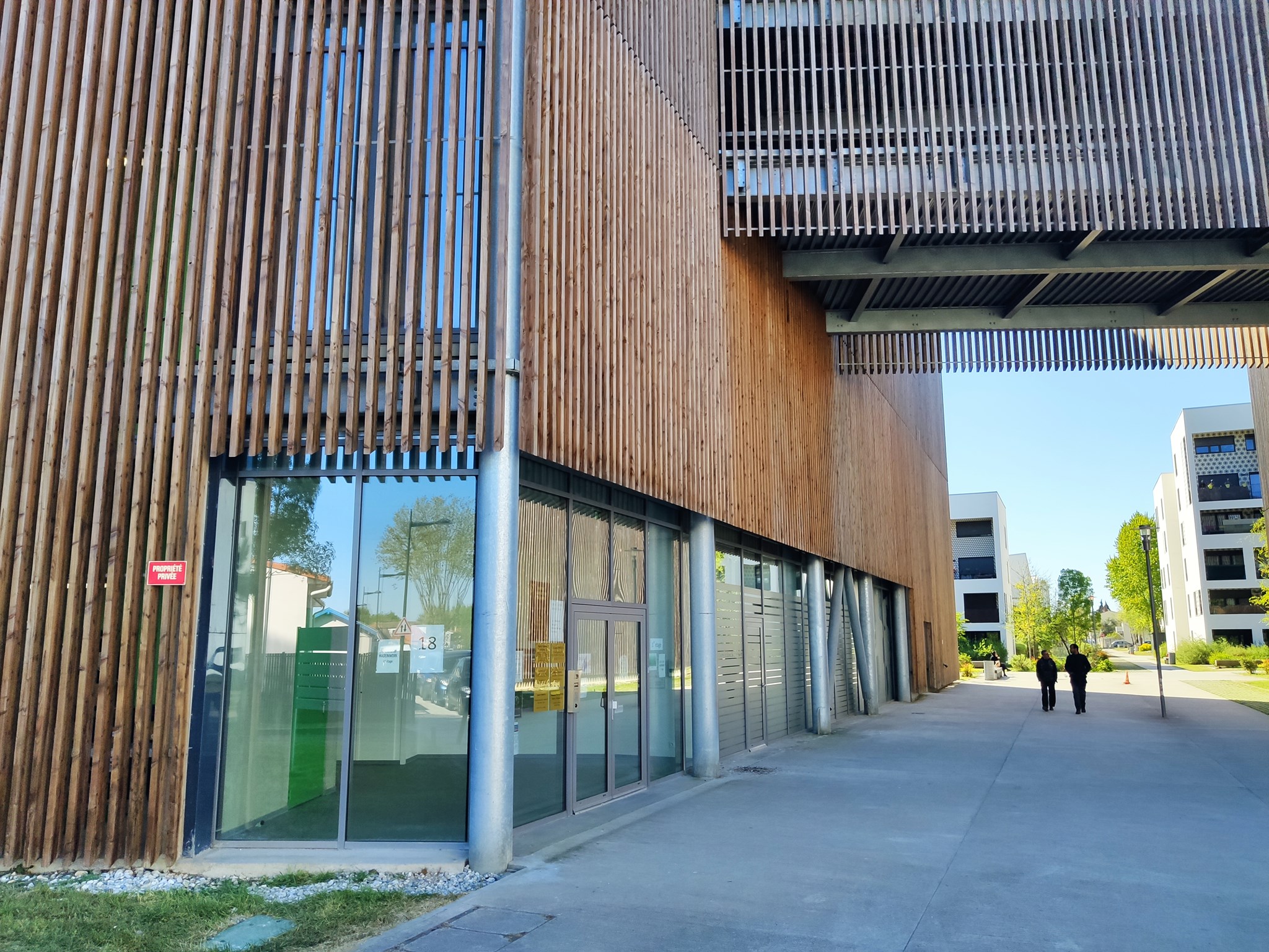 Façade d'entrée du bâtiment, avec des bris soleil en bois